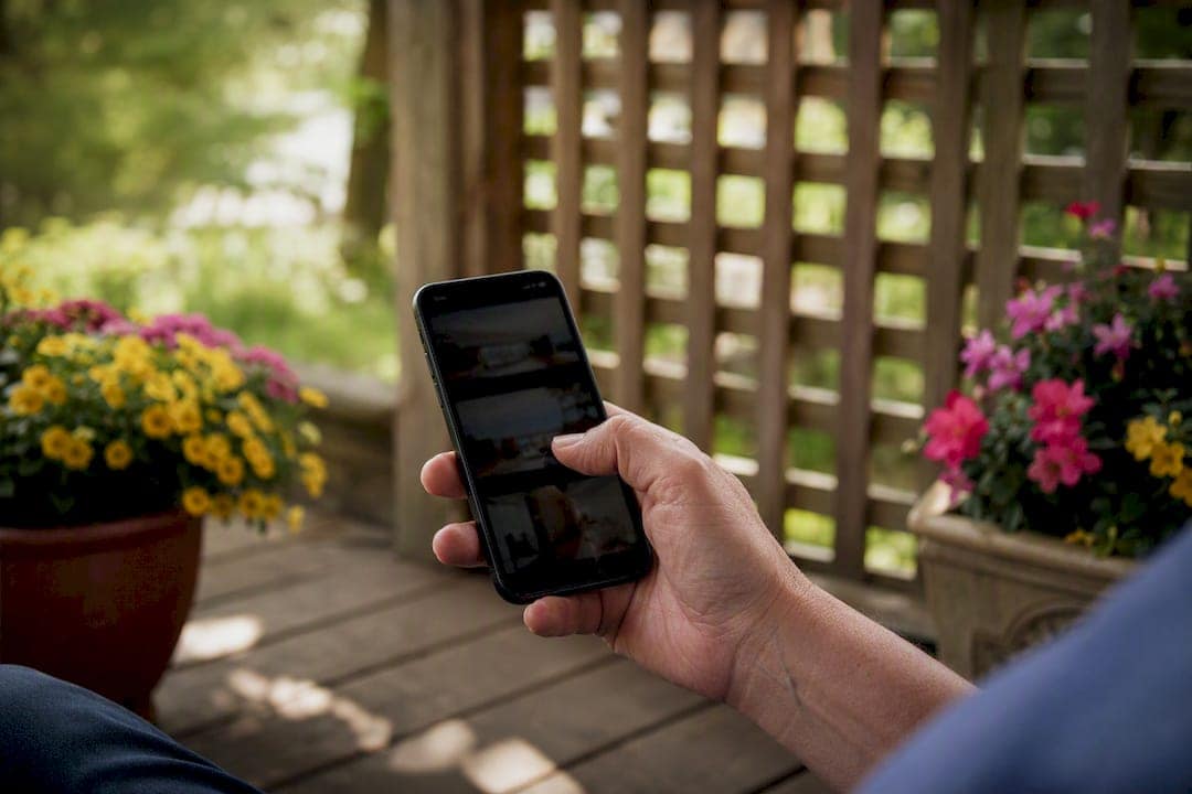 Hand holding smartphone showing project photos outdoors