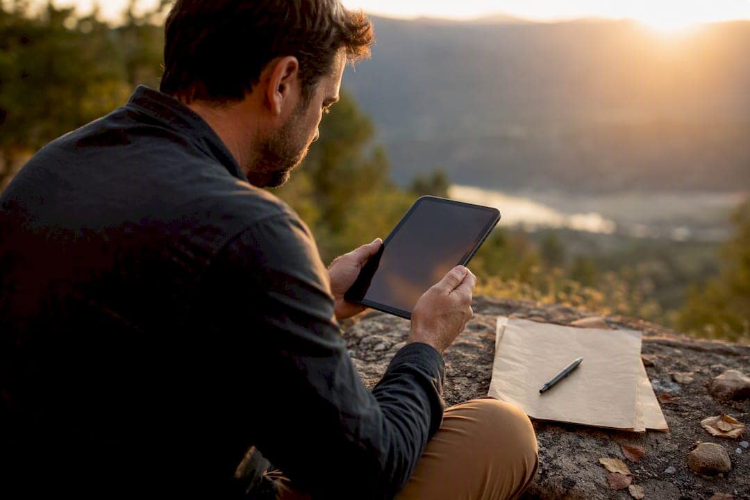 Hands holding tablet and notes on wooden table